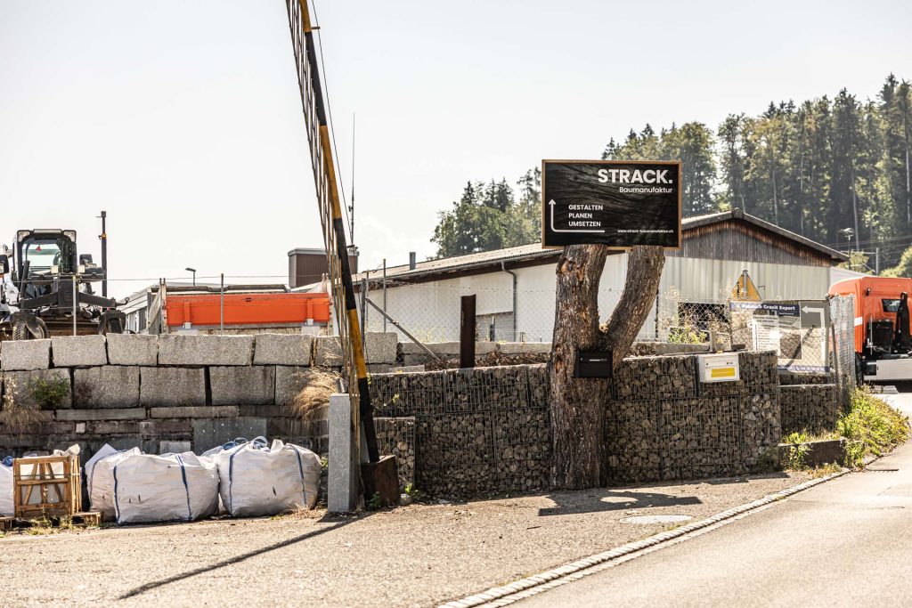 Werkplatz mit Firmenschild und Materiallager am Standort Flawil