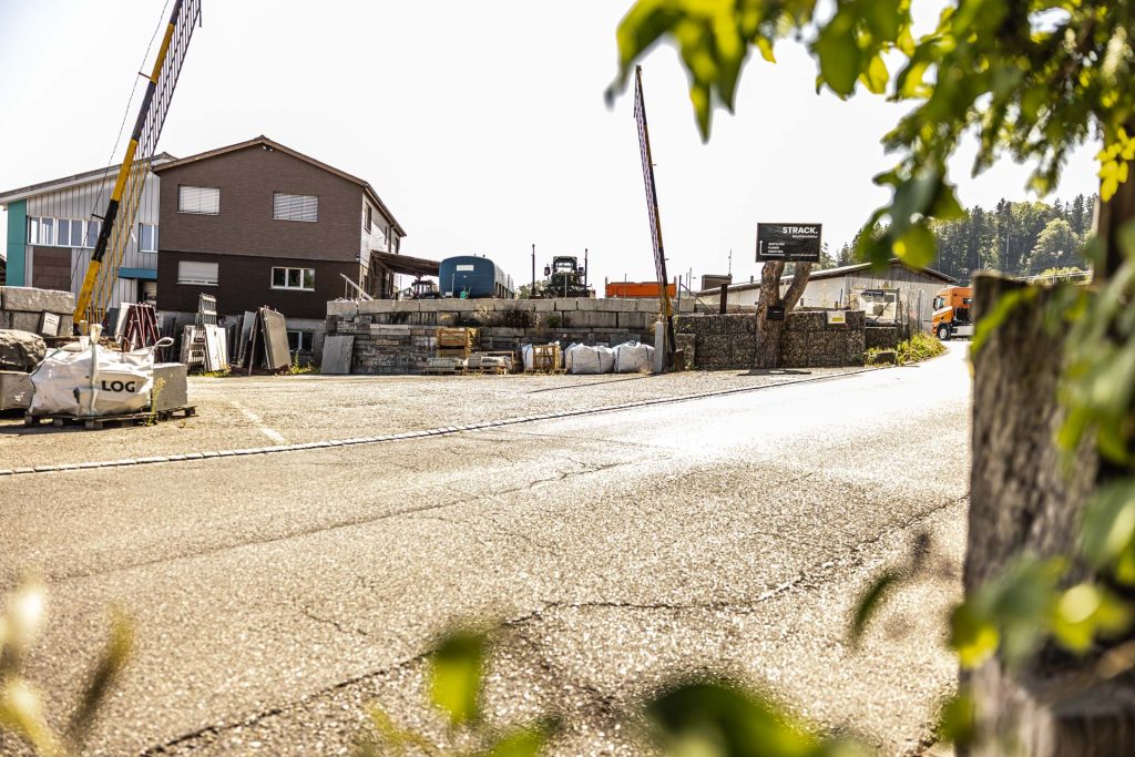Zufahrt zum Firmenareal mit Betriebsgebäude und Baukran