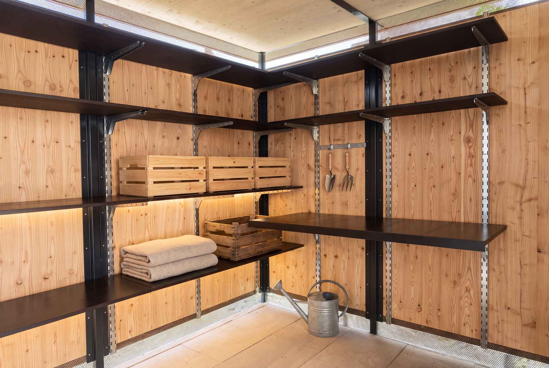 Innenausbau eines Geräteraums mit schwarzem Stahlregalsystem und Lärchenwänden