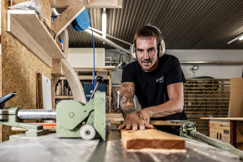 Schreiner der STRACK Baumanufaktur hobelt Kantholz an der Maschine