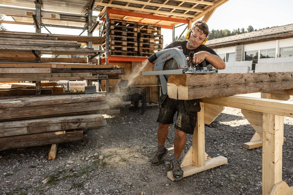 Zimmermann beim Balkenzuschnitt auf dem Werkplatz
