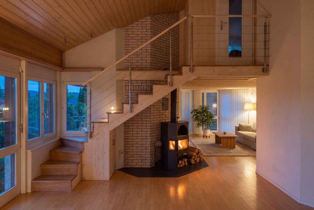 Innenausbau mit Massivholztreppe, Galerie und Schwedenofen im Abendlicht