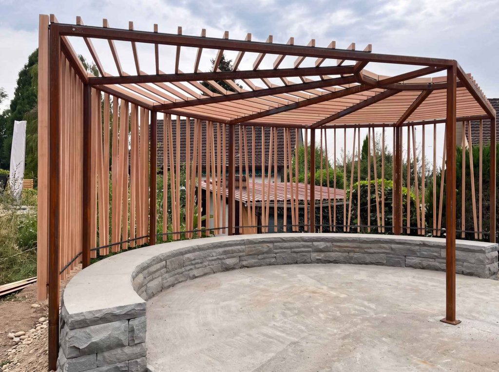 Pergola aus Cortenstahl und Holz über einem Sitzplatz im Garten