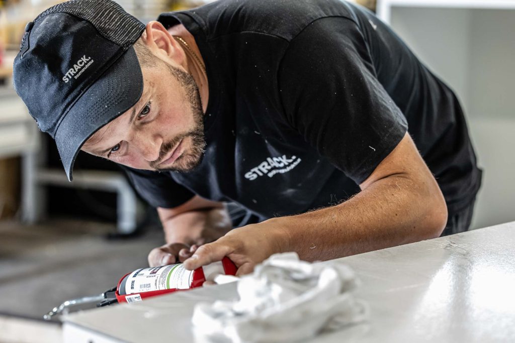 Mitarbeiter der STRACK Baumanufaktur verklebt sorgfältig eine Platte