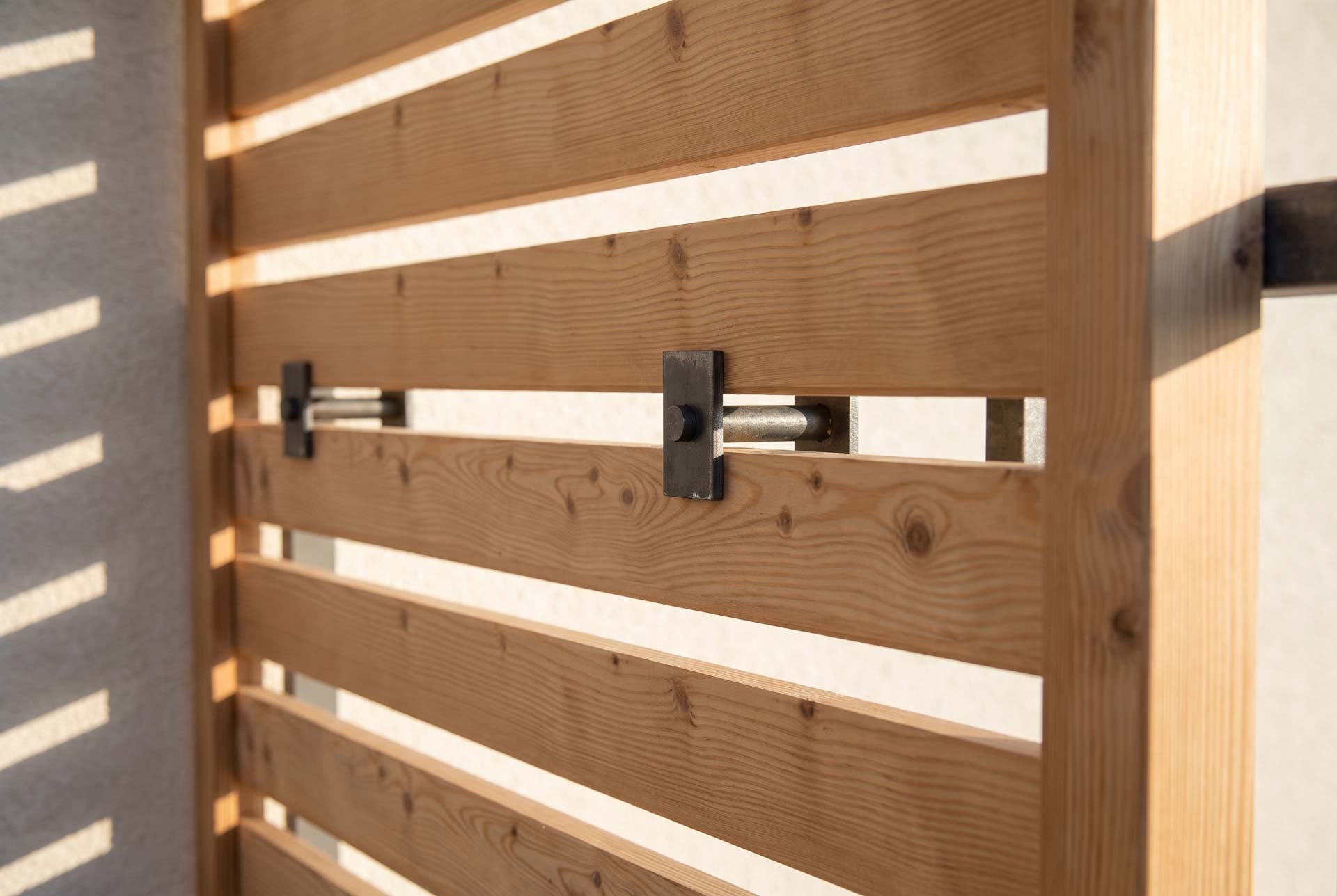 Detail des Lamellen-Sichtschutzes: Holzlatten auf schwarzer Stahlkonsole