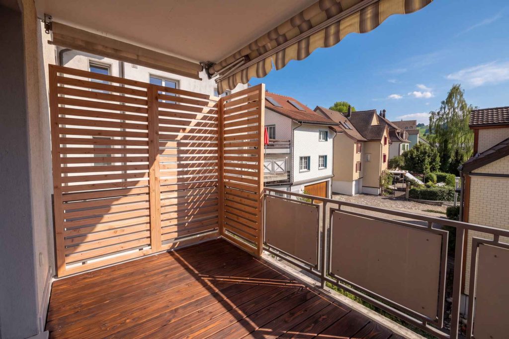 Balkon mit über Eck gestellten Sichtschutzelementen aus Holzlamellen und neuem Belag