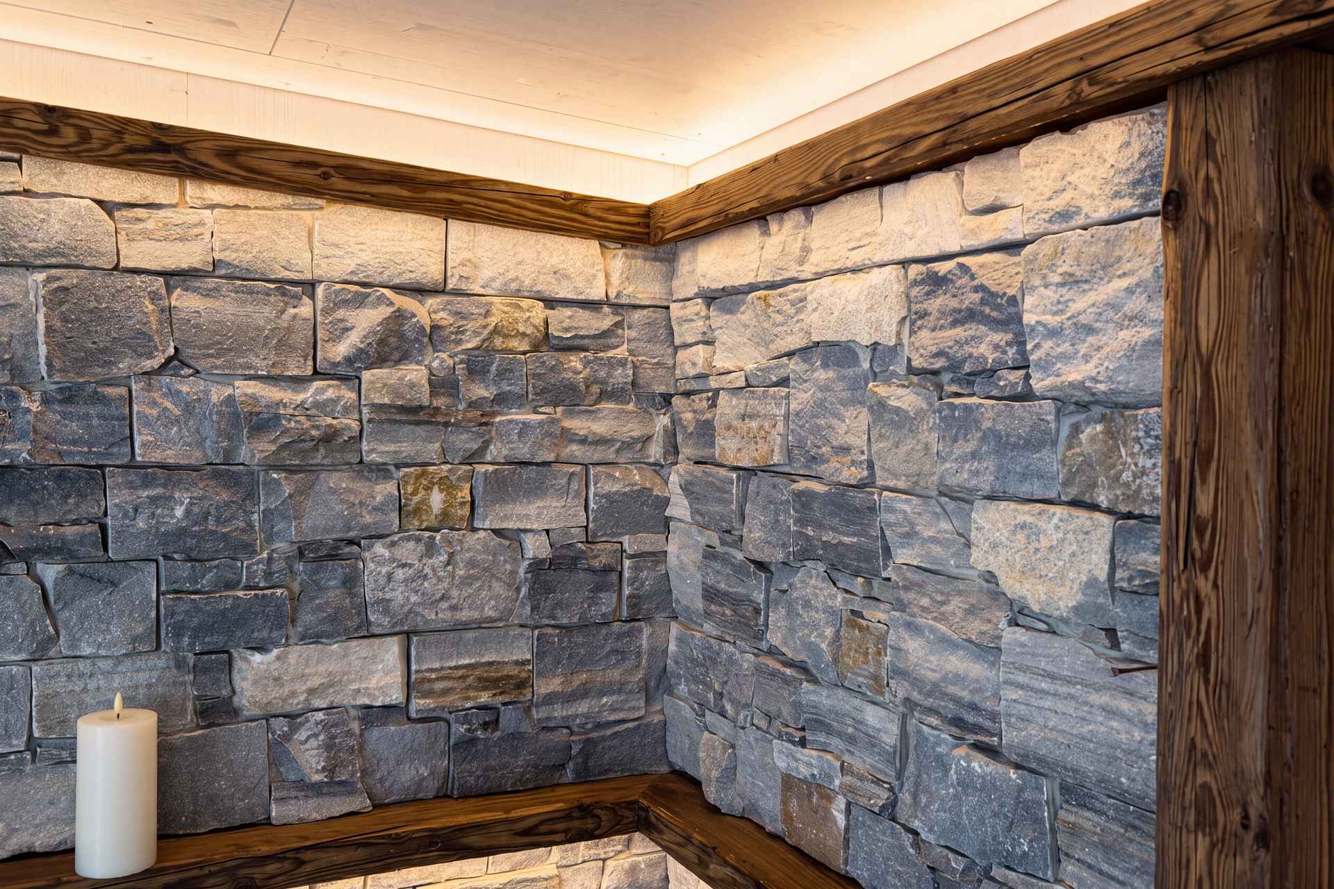 Detail der Natursteinwand mit Altholz-Eichenbordüre und indirekter Deckenbeleuchtung