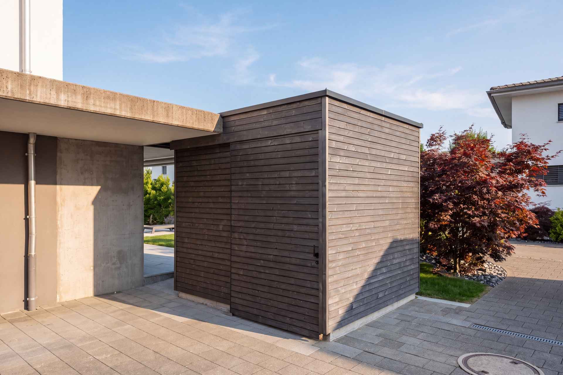 Gartenhaus zwischen Vordach und Sichtbeton, geschlossene Holzfassade