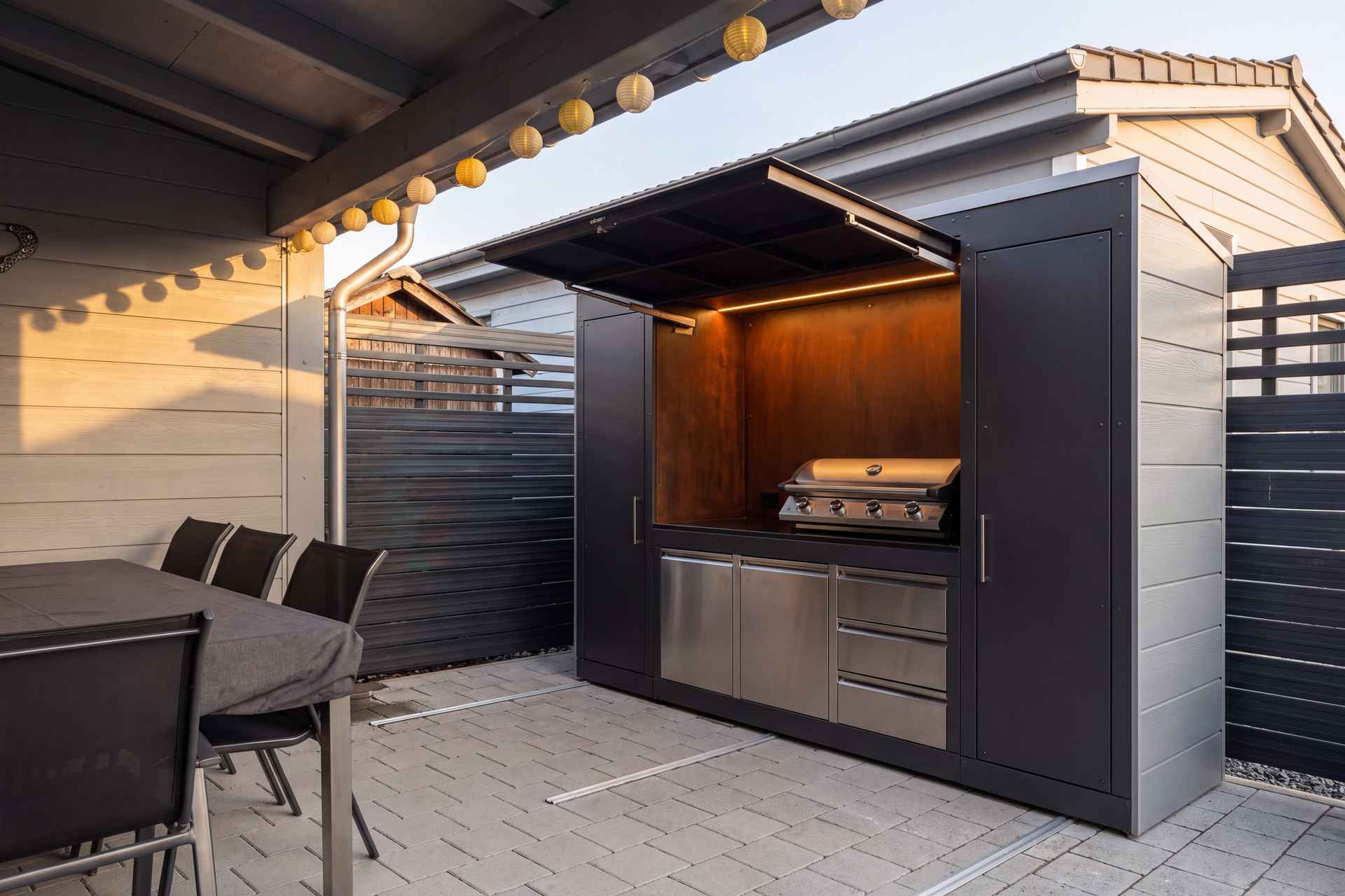 Geöffnete Outdoorküche mit Gasgrill, Edelstahl-Arbeitszone und Esstisch