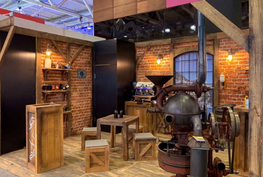 Messestand im Röstereistil mit Backsteinwand, Altholz und historischer Röstmaschine