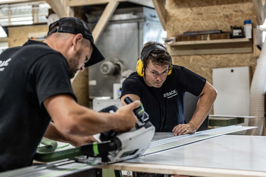 Zwei Mitarbeiter arbeiten beim Zuschnitt Hand in Hand